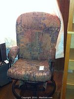 Fabric upholstered rocking chair with armrests, multicolor pattern, shows some wear