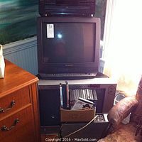 Panasonic TV with built-in VCR, Advest TV, box with DVDs beneath, and other electronics stored around.