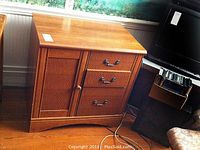 Front view of wood chest showing smooth top surface, three drawers with handles, and one door with knob.