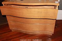 Side angled photo of wood chest of drawers showing its size, shape, and drawer design.