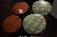 Top view of four round stools, two with wood tops and two with green plaid cushioned tops.