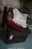 Wood children's desk with two cushions on top, seen from an angle showing wear on the wood surface.