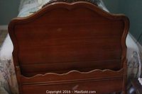 Twin size wood headboard showing curved top and polished brown wood finish with some wear and scratches.