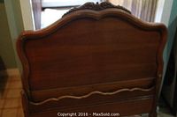 Wooden twin headboard with curved top and carved wood detailing in a dark finish, showing scratches and wear