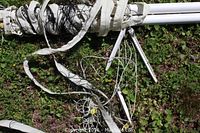 Close-up of volleyball net tangled and wrapped around white metal poles along with support cords, showing some wear.