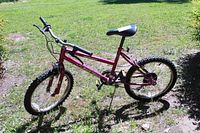 Side view of red Murray Back Track kids bike showing 6-speed gear system, black seat, and handlebars on grassy area
