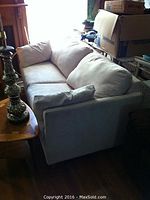 Pull out sleeper sofa in a room surrounded by boxes, visible couch cushions and armrests, shot showing sofa from a side angle.