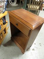 Closed drawer and overall view of the wood veneer night stand showing medium brown finish and wear.
