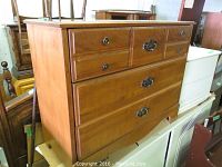 Wood veneer dresser with six drawers, showcasing metal pulls and medium brown finish.