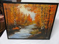 Full view of the oil on canvas painting showing a fall forest scene with a river and orange foliage, framed in a scratched black frame.