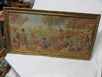 Full view of framed tapestry showing figures in traditional attire by water with gazebo and bridge background.