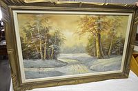 Framed oil on canvas painting showing winter landscape with snow-covered path, trees with yellow and brown leaves, and diffuse yellow sky.