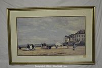 Framed print showing a beach scene with people and large buildings along the shoreline.