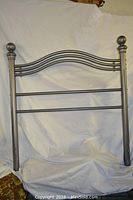 Twin size metal headboard with curved horizontal bars and rounded finials, showing scratches.
