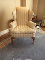 Front view of the wingback chair showing striped upholstery and wood legs.