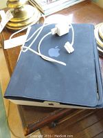 Black folio case closed around iPad with 30-pin USB cable and power adapter on top