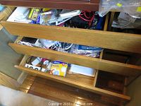 Open wooden drawers filled with assorted cables, electric cords, small accessories, manuals, and other AV supplies.