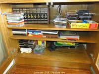 Wooden shelving containing stacks of CDs, blank media spindle, slim case box and encyclopedia volumes