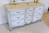 Full front view showing six curved drawers, painted finish and brass-tone handles.