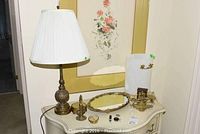 Photo showing the vintage filigree brass lamp with pleated white shade, matching brass perfume bottle, needlepoint dish, mirror tray with small boxes, and brass scales arranged on a dresser.
