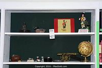 Full shelf view showing decorative items including Buddha statue, plastic duck, vintage Scottish sign, Dewar's Highlander figurine, brass cannon, and globe.
