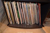 Photo of a shelf fully packed with numerous vinyl LP records, spines mostly visible showing a sizable collection.