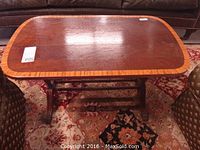 Full view of the small rectangular wooden trestle coffee table showing the reeded trim and brass claws on the feet.