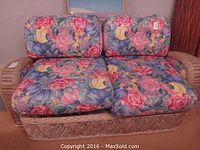 Front view of wicker loveseat with floral cushions
