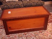 Closed view of rectangular wooden storage cabinet with light wood panel and dark brown trim, showing the top and front sides.