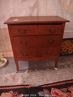 Front view of vintage dresser showing three drawers with metal handles, wood construction, and casters beneath.