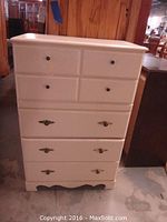 Full front view of the cream-colored dresser showing five drawers and bracket feet