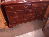 Full front view of vintage dark wood dresser showing eight drawers with brass tone metal handles.