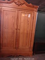 Full view of solid pine country style armoire with tall double doors and arched top with carved decoration.