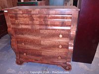 Front view of antique wooden dresser with four drawers and rounded wooden knobs, showing the curved front design and wood grain pattern.