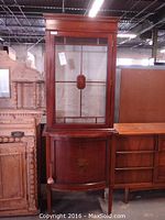 Full view of two-piece display cabinet showing upper glass section and bowed lower cabinet.