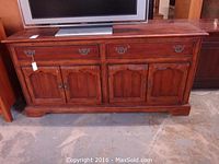 Full front view of wood credenza showing two drawers with metal pulls and four cabinet doors beneath, reddish-brown wood finish.