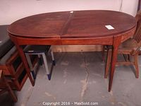 Full view of the oval teak table showing tapering legs and overall shape