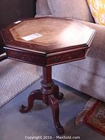 Full view of the octagonal wood swivel top side table showing reddish-brown finish and tripod base.