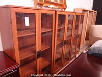 Three identical wood and glass cabinets displayed side by side