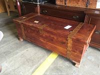 Wood trunk with copper straps on all corners and top, showing wear and scratches.