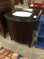 Side angled view of the Baker sink cabinet with dark wood, vertical panels, marble top and white rectangular sink cutout visible.