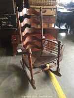Front angle showing carved floral back slats, rush seat, and general chair structure.