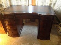 Front view of desk showing overall shape, mahogany finish, and drawer layout