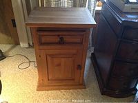 Front view of closed pine cabinet showing single drawer and door