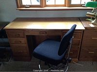 Full view of oak desk with office chair in front, showing desk top and drawer configuration.
