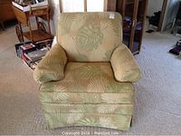 Front view of the yellow and green fern patterned armchair showing cushion and skirted base