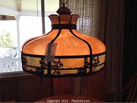 Overall view of the lit slag glass chandelier showing glass shade and metal frame