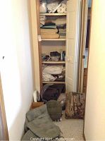 Closet with various stacked chair cushions and a throw pillow on the floor in front