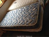 Blue patterned mattress and low profile boxspring on metal frame in corner of room