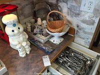 Photo of Pillsbury Doughboy cookie jar, matching salt and pepper shakers, serving trays, popcorn maker, and small kitchen accessories on a countertop.